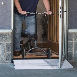 Man exiting door on knee scooter with aid of threshold ramp