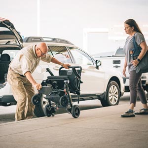 Man retrieving power wheelchair from the back of vehicle